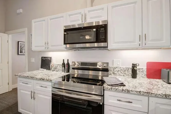 a kitchen with granite countertop white cabinets and stainless steel appliances