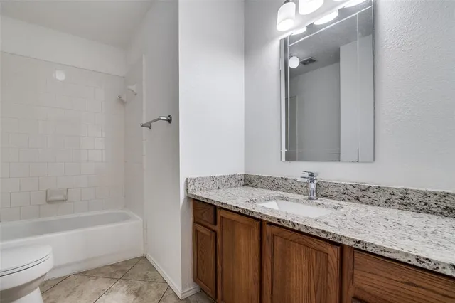 a bathroom with a granite countertop bathtub sink vanity mirror and toilet