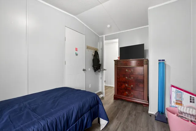 a bedroom with a bed and a flat tv screen on dresser