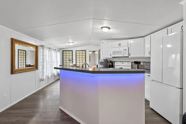 a kitchen with stainless steel appliances granite countertop a stove a refrigerator a sink a refrigerator white cabinets and wooden floor