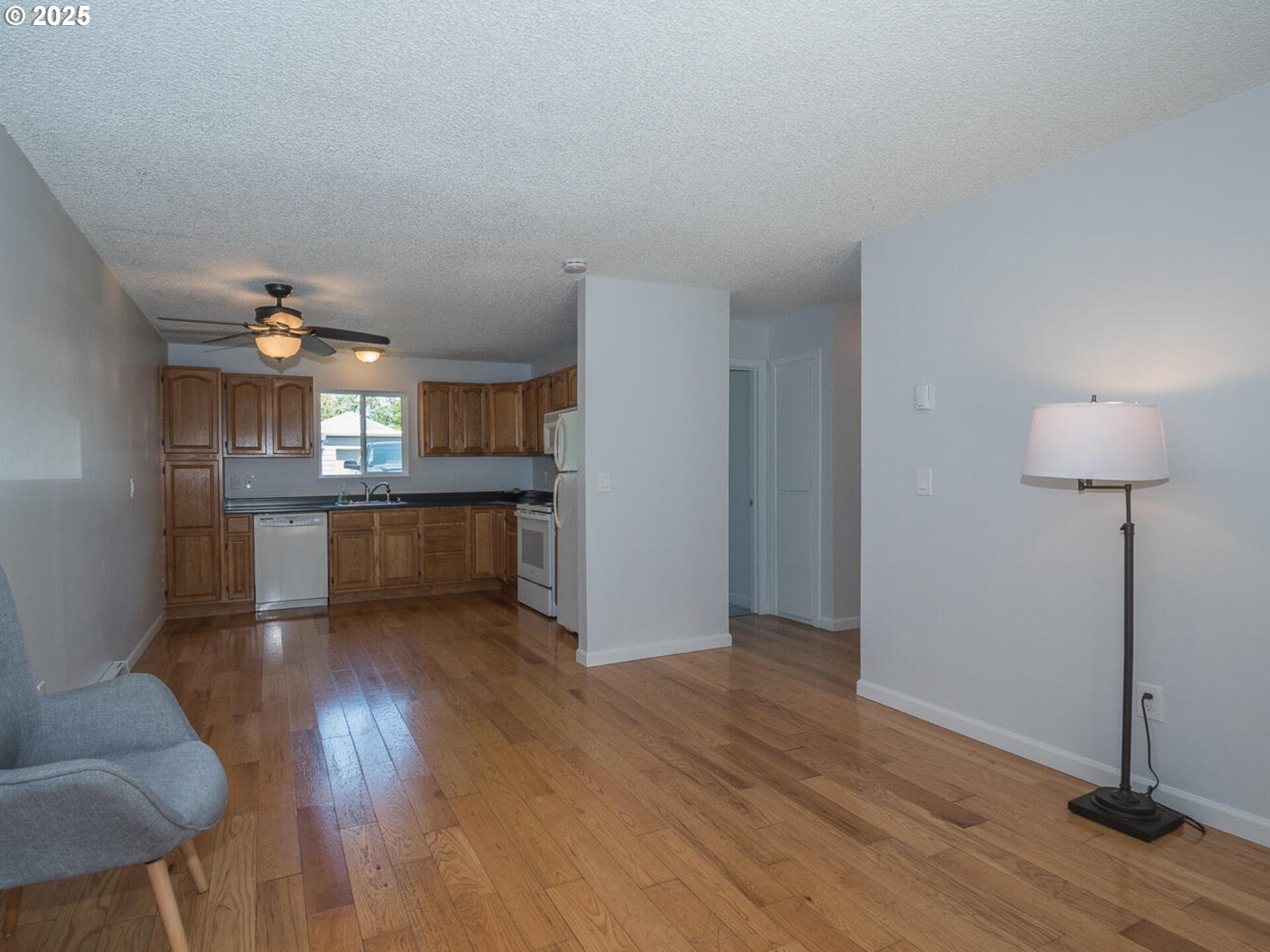 2712 Southeast 138th Avenue, Unit 53 Portland, OR 97236 - Photo 5 of 36 a view of a kitchen and an empty room with wooden floor and a kitchen