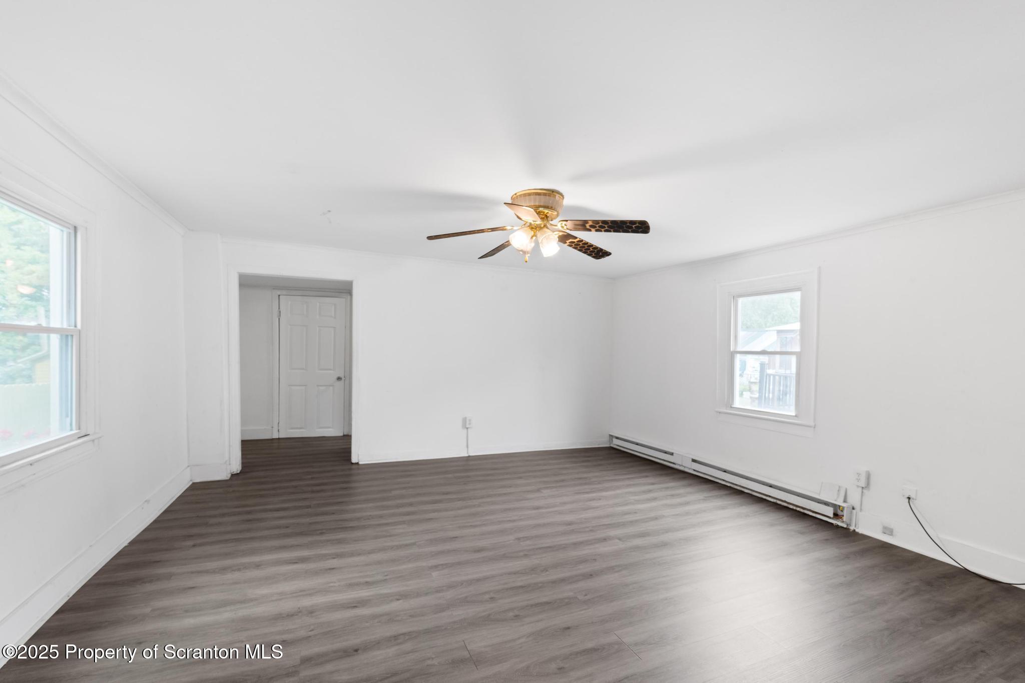 121 Throop Street Scranton, PA 18508 - Photo 18 of 37 an empty room with wooden floor chandelier fan and windows