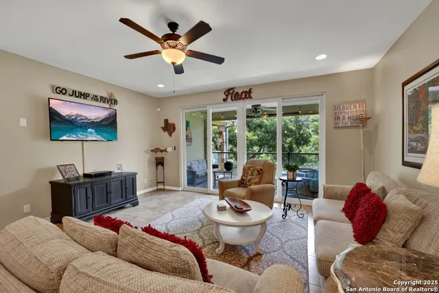 a living room with furniture ceiling fan and a large window