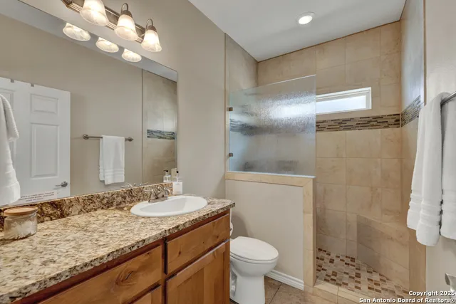 a bathroom with a granite countertop sink toilet and shower