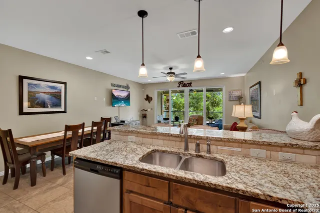 a kitchen with granite countertop a sink a counter top space and living room view