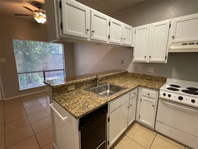 a kitchen with granite countertop a sink stove and cabinets