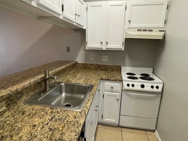 a kitchen with granite countertop a sink a stove and cabinets