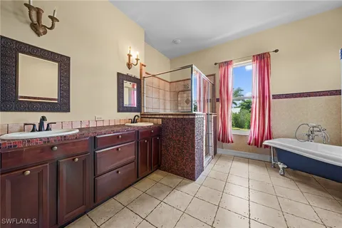 a spacious bathroom with a granite countertop sink a mirror and a bathtub