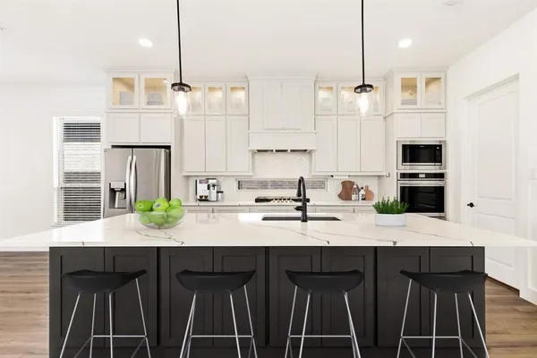 a kitchen with kitchen island granite countertop a sink cabinets and stainless steel appliances