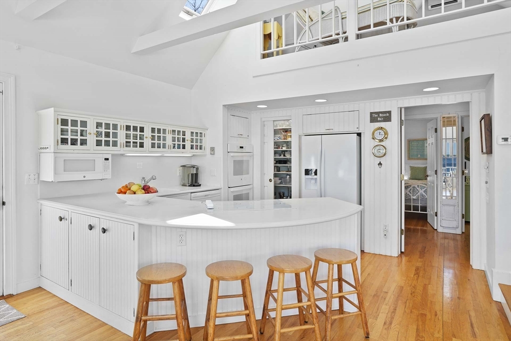 31 The Boulevard Edgartown, MA 02539 - Photo 14 of 39 a kitchen with stainless steel appliances kitchen island granite countertop a refrigerator a stove and white cabinets with wooden floor