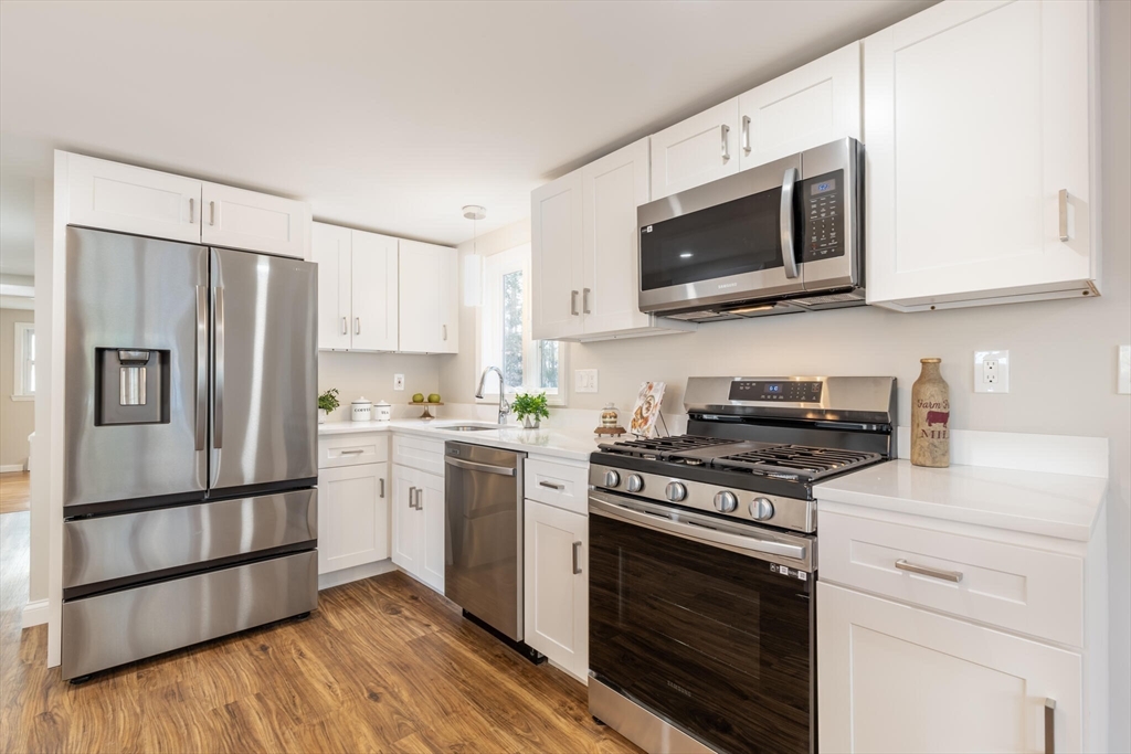123 Lowell Road Pepperell, MA 01463 - Photo 4 of 30 a kitchen with stainless steel appliances white cabinets a stove a microwave and a refrigerator