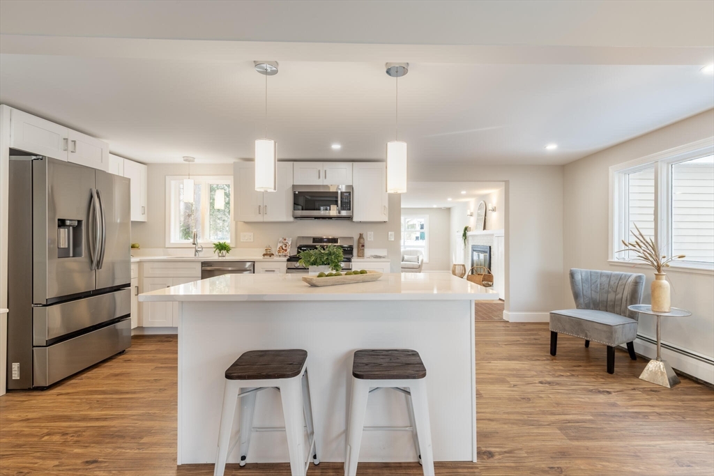 123 Lowell Road Pepperell, MA 01463 - Photo 5 of 30 a kitchen with stainless steel appliances kitchen island granite countertop a refrigerator a stove a sink dishwasher and a dining table with wooden floor