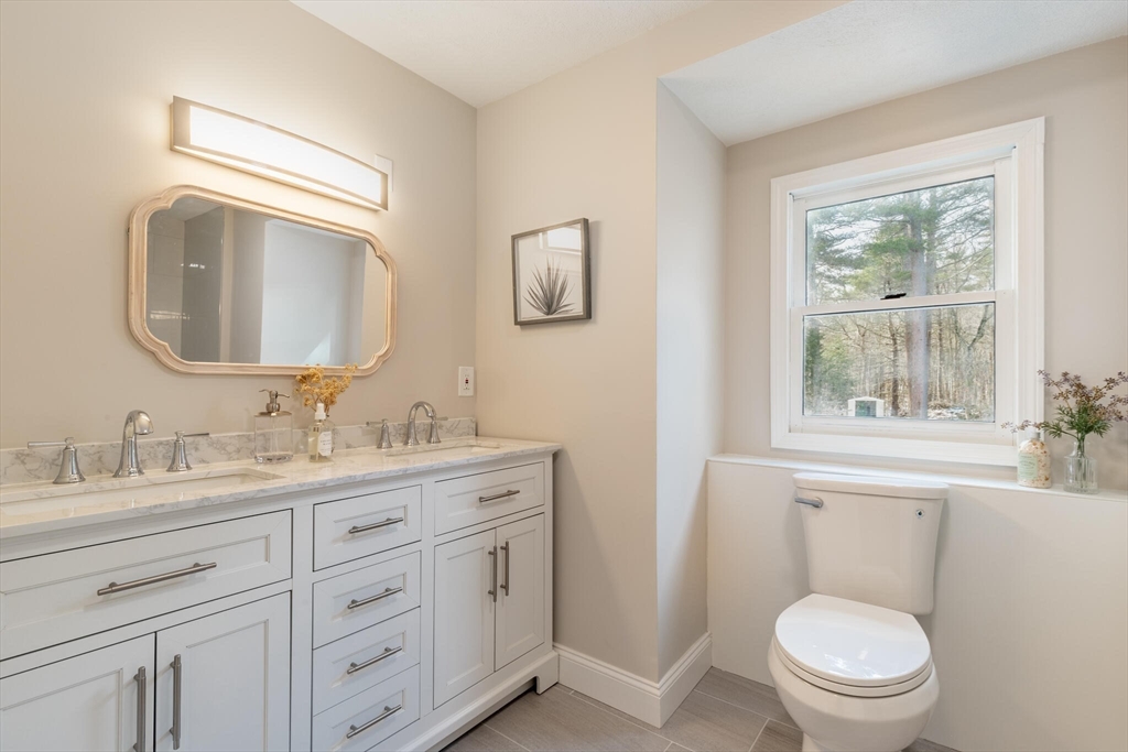 123 Lowell Road Pepperell, MA 01463 - Photo 10 of 30 a bathroom with a toilet a sink a vanity a window and mirror