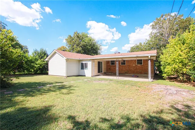 a view of a house with a backyard and a tree