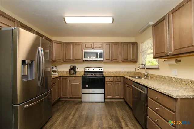 a kitchen with a refrigerator sink and wooden cabinets