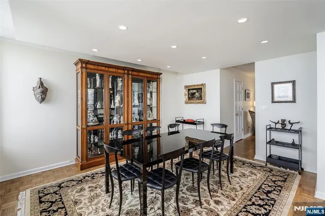 a kitchen with stainless steel appliances granite countertop a stove top oven a sink a dining table and chairs with wooden floor