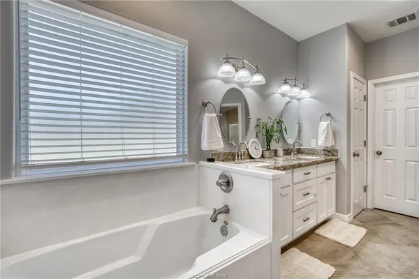 a bathroom with a double vanity sink mirror and a bathtub with shower