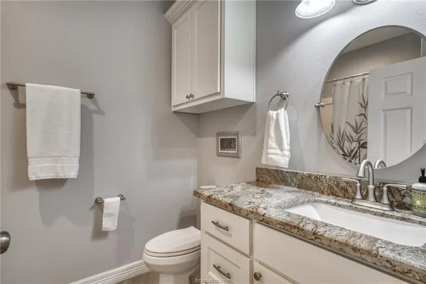 a bathroom with a granite countertop sink a toilet and a mirror
