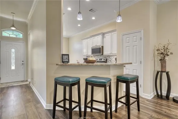 a kitchen with granite countertop white cabinets and stainless steel appliances