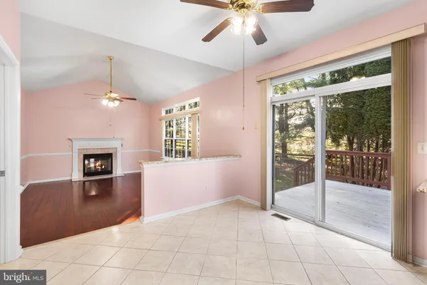a view of an empty room with window and kitchen view