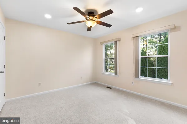 an empty room with window and ceiling fan