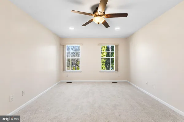 an empty room with windows and ceiling fan