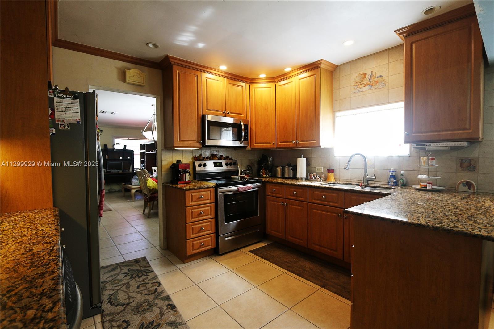 842 Southwest 89th Avenue, Unit A Miami, FL 33174 - Photo 12 of 34 a kitchen with stainless steel appliances kitchen island granite countertop a sink dishwasher stove and refrigerator with wooden floor