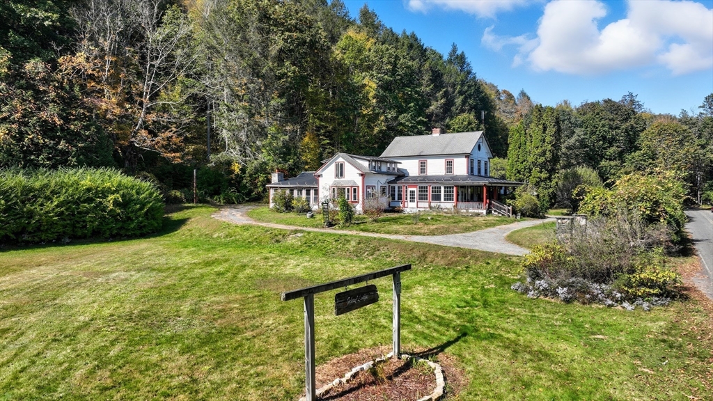 a view of a house with a big yard and large trees