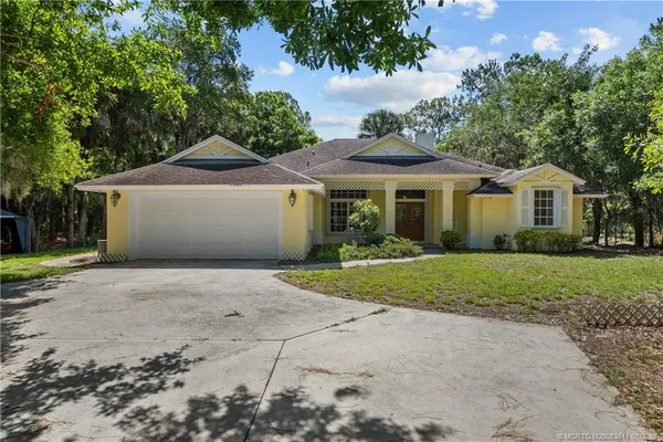 a front view of a house with a yard and trees