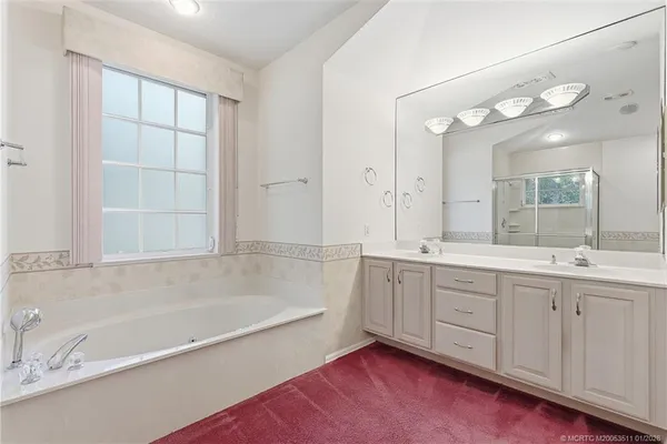 a spacious bathroom with a tub sink and mirror
