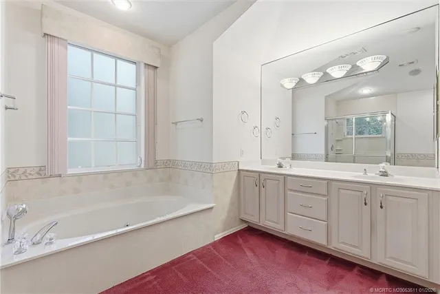 a spacious bathroom with a tub sink and mirror