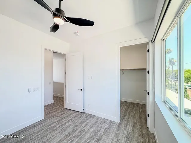 an empty room with wooden floor cabinet and windows