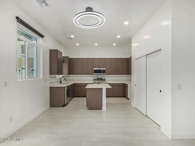 a large kitchen with a large counter top a sink stainless steel appliances and cabinets