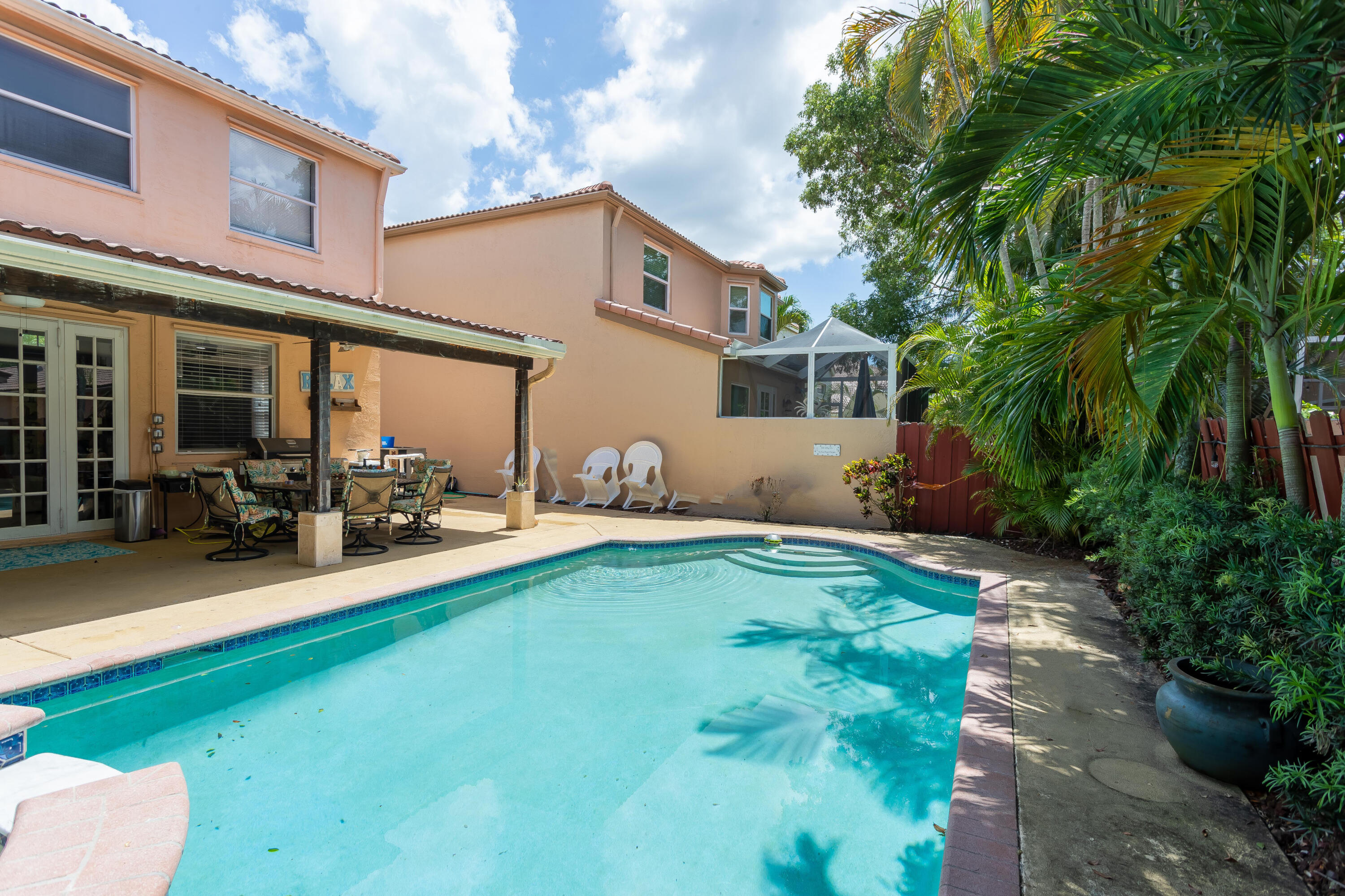 7855 Oak Grove Circle Lake Worth, FL 33467 - Photo 21 of 40 a view of a patio with table and chairs potted plants and a large tree