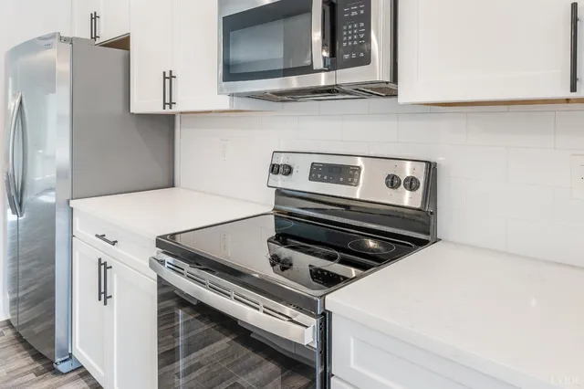 an empty room with wooden floor chandelier fan and windows