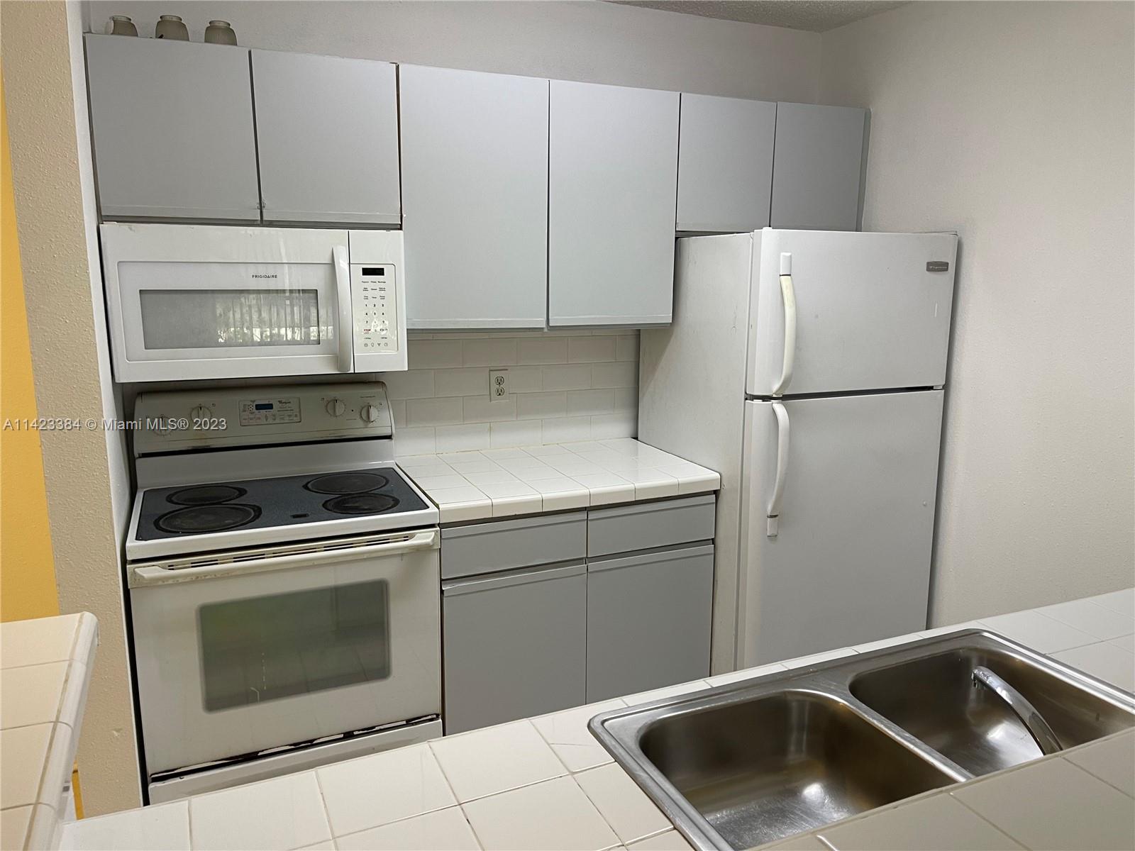 4045 West McNab Road, Unit G106 Pompano Beach, FL 33069 - Photo 16 of 23 a kitchen with a refrigerator sink stove and cabinets
