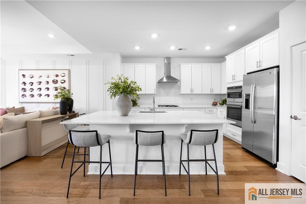 a kitchen with stainless steel appliances kitchen island granite countertop a dining table chairs and refrigerator