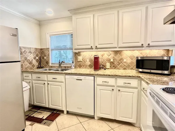 a kitchen with granite countertop white cabinets and white appliances