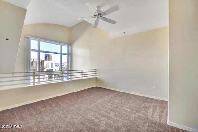 an empty room with chandelier fan and windows