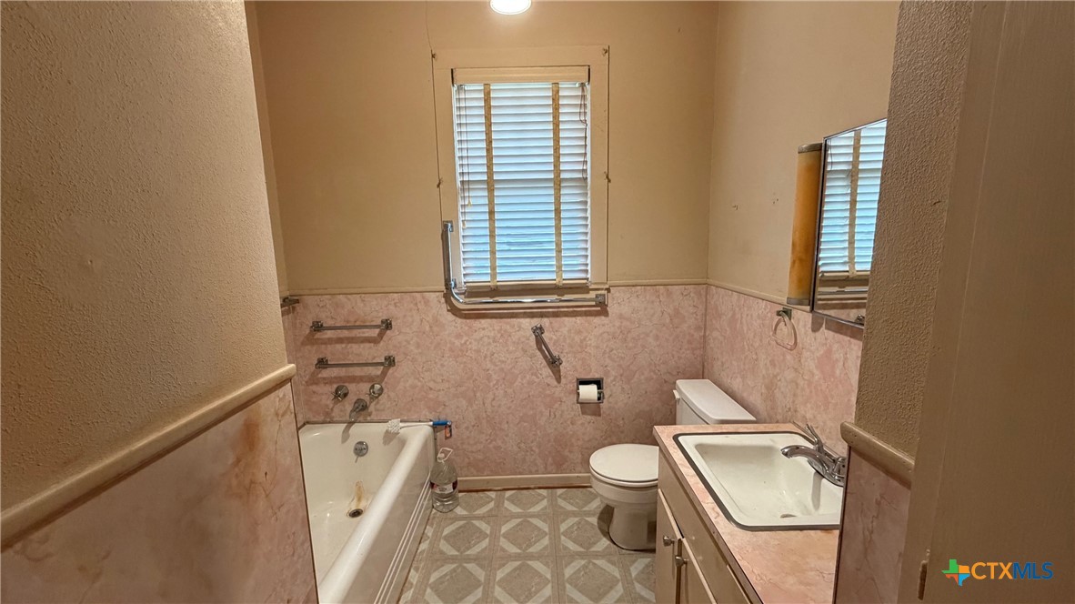 701 East 10th Street Cameron, TX 76520 - Photo 9 of 19 a bathroom with a granite countertop toilet sink and mirror