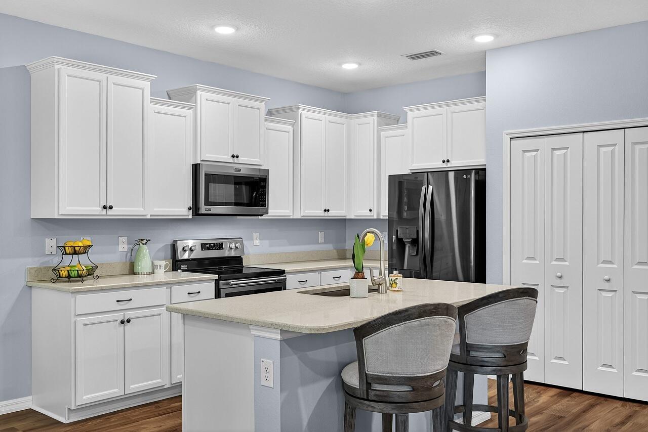 313 Sandcrest Circle Sebastian, FL 32958 - Photo 12 of 42 a kitchen with stainless steel appliances granite countertop a sink a microwave a refrigerator and white cabinets