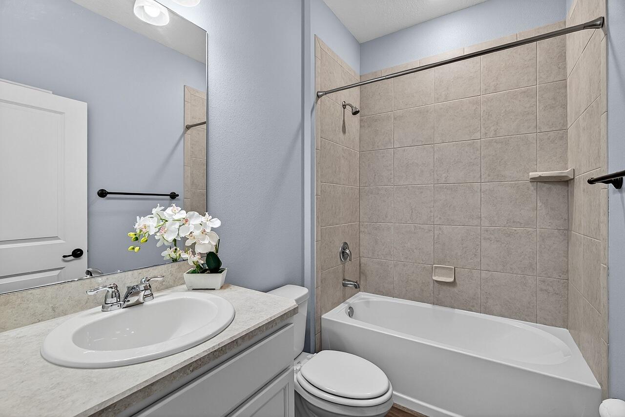 313 Sandcrest Circle Sebastian, FL 32958 - Photo 30 of 42 a bathroom with a granite countertop sink toilet a mirror a bathtub and shower