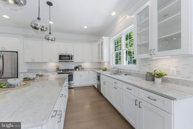 a kitchen with kitchen island granite countertop a sink stainless steel appliances cabinets and a window