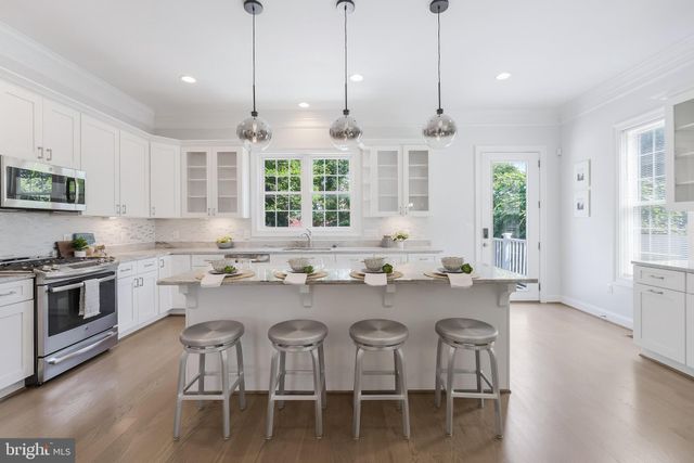 a kitchen with stainless steel appliances granite countertop a stove a sink a window a dining table and chairs