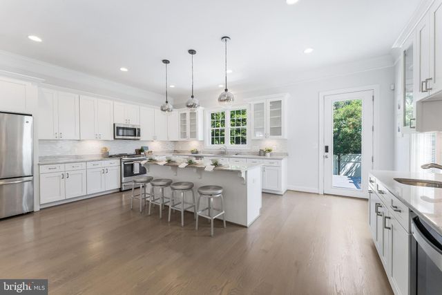 a large white kitchen with lots of counter space a sink appliances and a large window