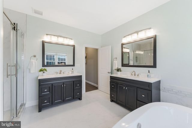 a bathroom with a double vanity sink mirror and bathtub