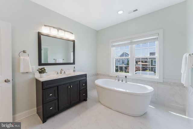 a spacious bathroom with a double vanity sink mirror and bathtub