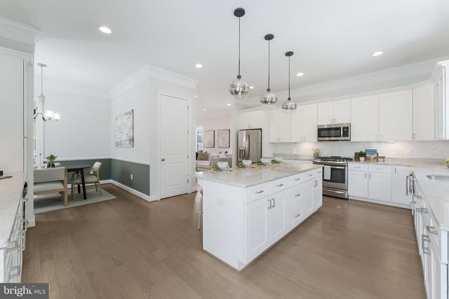 a large kitchen with kitchen island a large counter space a sink stainless steel appliances and cabinets