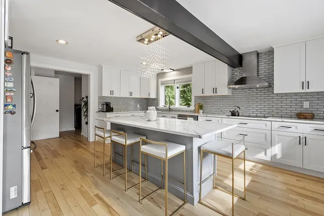 a kitchen with stainless steel appliances granite countertop a table chairs sink and cabinets