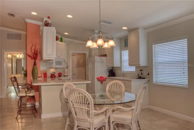 a view of a kitchen with granite countertop a dining table chairs and a white refrigerator